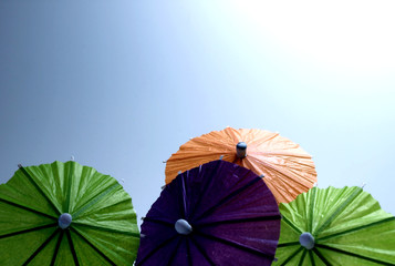 Colorful umbrellas in front of cloudless blue sky with sun
