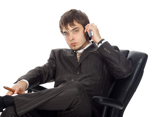 young businessman sitting in an armchair and smiling speaking on