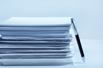 a pen near stack of paper