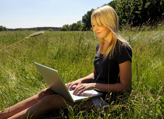 Junge Frau mit Laptop auf einer Wiese