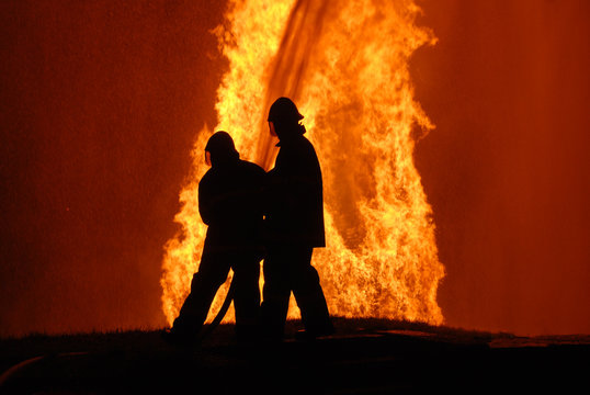 two firemen battling against raging fire