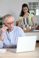 Femme senior au téléphone devant ordinateur