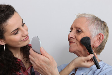 Jeune femme maquillant une femme senior