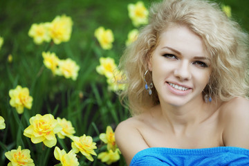 Beautiful positive girl in a park, surrounded by flowers