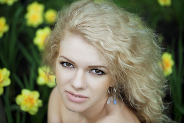 Beautiful positive girl in a park, surrounded by flowers