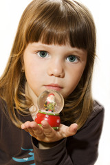 Naklejka premium Little girl hold Santa claus figurine on a glass snowing ball