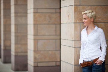 blonde frau lehnt an einer mauer