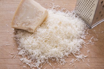 Shredded Parmeson Cheese On A Cutting Board With A Grater