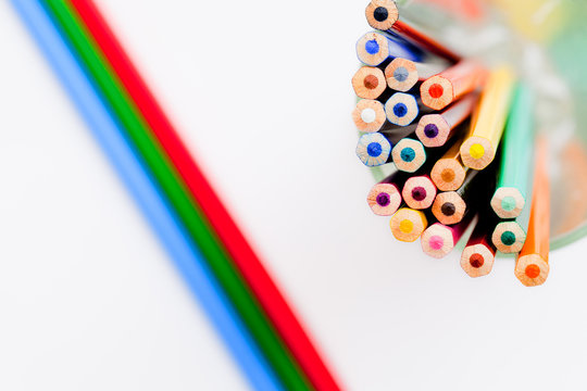 multicolored pencils in a glass on a white background