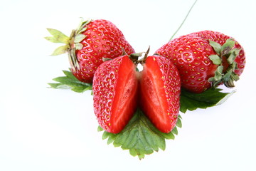 Strawberries on a leaf, one cut in half, on white background