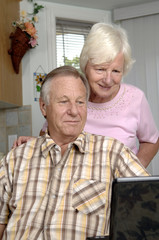 Senior couple browses Internet on their laptop.