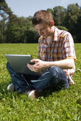 Obraz premium Young man using laptop in summer park