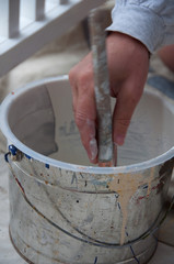 Hand of Exterior House Painter Dipping Brush in Pail