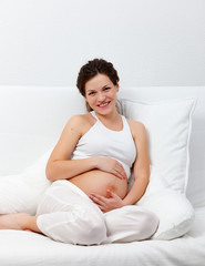 Obraz na płótnie Canvas Young pregnant woman sitting on sofa