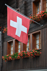 andermatt, bandiera svizzera su facciata con geranei