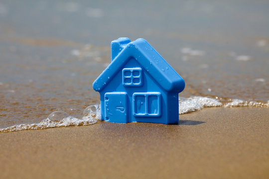 Toy Plastic House On The Sand Washes Wave