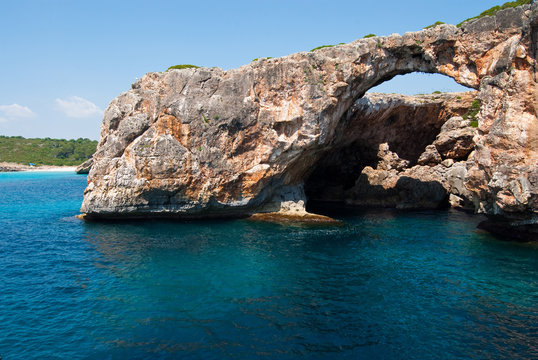 Transparent water and the natural rocky arch at Cala Antena, Maj - Powered by Adobe