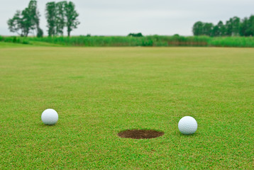 Two golf balls near the hole
