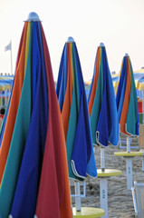 Line of multicolored closed beach umbrellas, Rimini
