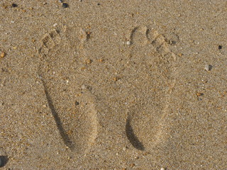 trace de pieds sur le sable d'une plage
