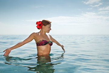 Sexy red girl wearing bikini standing in the ocean