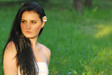 Naklejka premium young girl with flower looking opposite green copy space