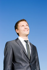 Successful businessman in a suit against the blue sky