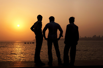 3 Indian guys watch the sunset over Mumbai