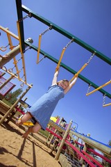 Child Swinging On Monkey Bars At Playground