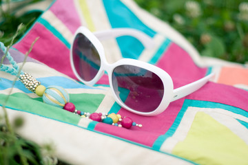 Sunglasses and bright bag lying on the grass