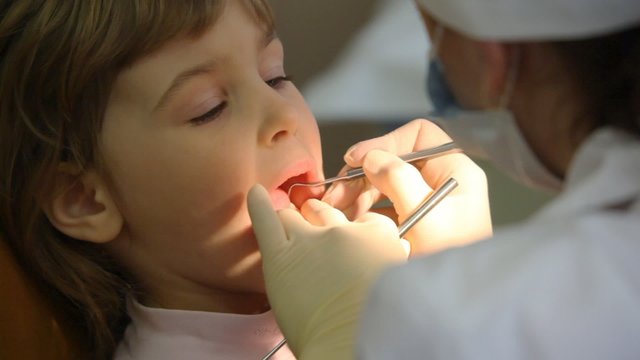 female dentist treats teeth of girl