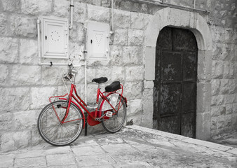 Red bicycle leaning against wall.