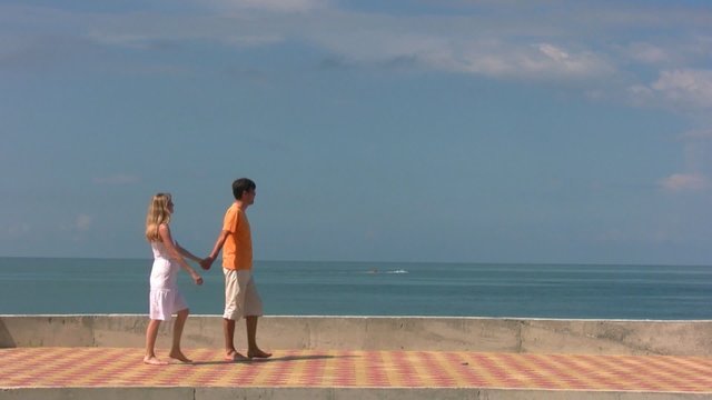 couple walks, then man holds woman looks at sea with cutter