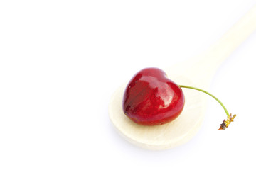 Cherries in a wooden spoon isolated on white