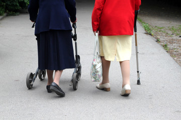 Zwei alte Frauen mit Gehwagen und Stock im Park