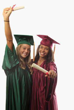 two female graduates in cap and gown with diplomas