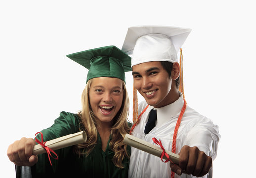two graduates in cap and gown with diplomas