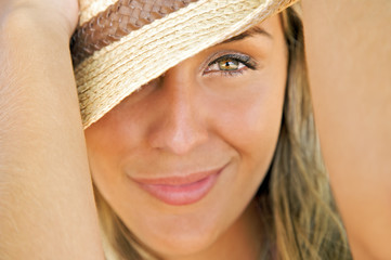 portrait of a young blond model holding a straw hat up close