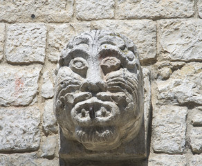 Ancient stone face carved on brickwall.