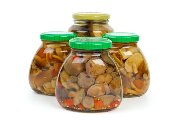 Four glass jars with marinated mushrooms