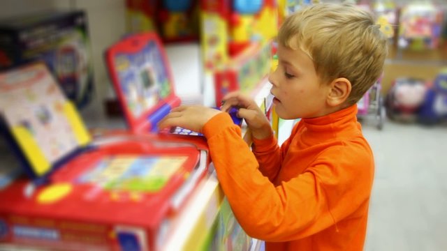 boy pushes buttons of electonic toy in shop