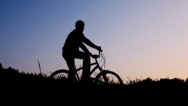 silhouette of man riding bicycle stops against sky