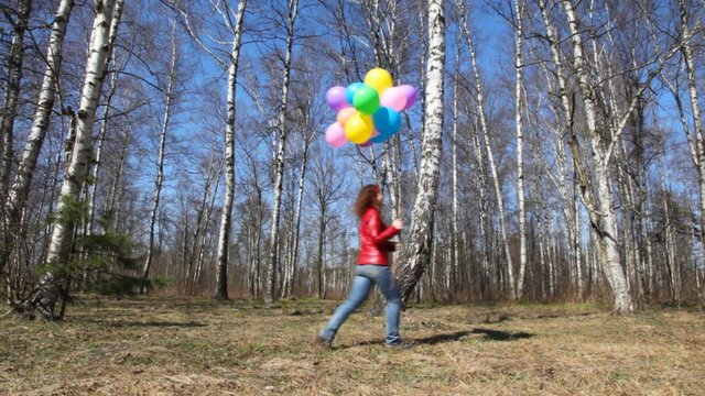 woman with balloons walks in grove