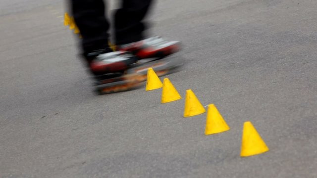Experienced roller skater rides in park among yellow cones