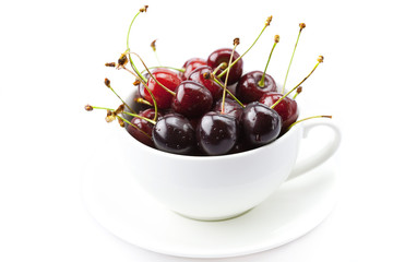 cherry in a cup and saucer isolated on white