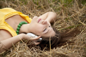 Young beautiful girl in yellow with headphones at field.