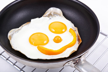smiling fried egg's face on the frying pan