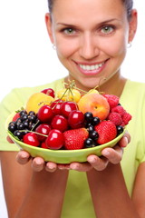 Smiling young woman keep full plate of berries.