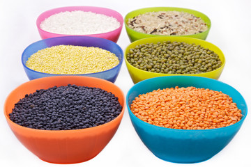 different cereals in six multicolored bowls isolated on white