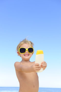 child with sunglasses showing suncream